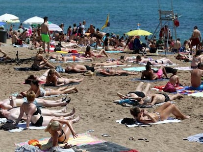 Banyistes prenent el sol a la platja de la Barceloneta.