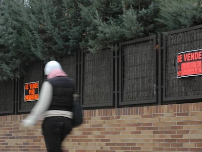 Una mujer camina por delante de una vivienda en venta.