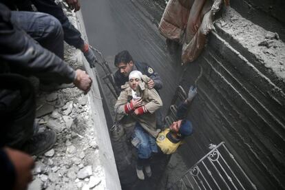 Miembros de la Defensa Civil de Siria ayudan a una mujer a salir de un refugio en la ciudad de Duma, el 22 de febrero de 2018.