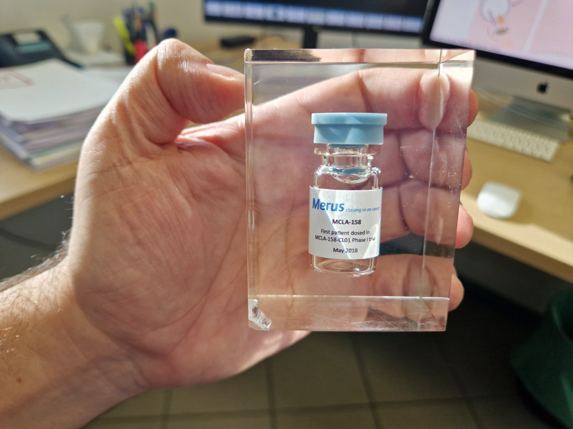 El frasco del primer tratamiento con petosemtamab en humanos, sujetado por Eduard Batlle en su despacho de Barcelona.