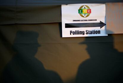 Las sombras de dos policias se refleja en la carpa de un colegio electoral, en Harare.