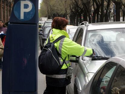 Una empleada del SER multa un vehículo en una calle de Madrid.