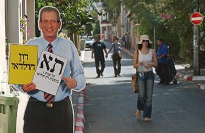 Varios israelíes caminan junto a un poster del alcalde de Tel Aviv, Ron Huldai, que ha sido reelegido.