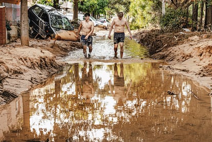 Dos jóvenes caminan entre el fango el día después del paso de la dana en la localidad de Picanya, el 30 de octubre. 