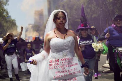Una mujer disfrazada con un vestido de novia y moretones simulados con maquillaje, protesta contra la violencia machista.