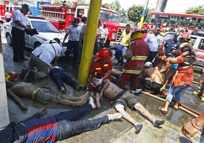 Los bomberos tratan de ayudar a heridos en el incendio junto a los cad&aacute;veres. 