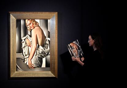 Una empleada de Christie's revisa un catálogo junto a 'Retrato de Marjorie Ferry, de Tamara de Lempecka.