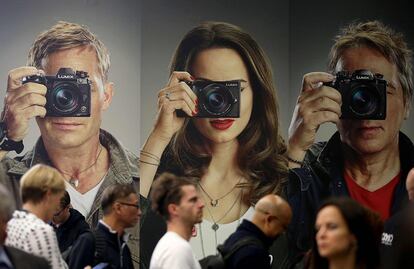 Asistentes a la feria Photokina pasan frente a una publicidad de Lumix, el 26 de septiembre, en Colonia.  