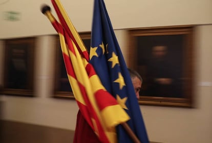 Un trabajador de la sede de la patronal catalana Fomento del Trabajo en Barcelona, coloca unas banderas de Catalu&ntilde;a, Espa&ntilde;a y Europa.