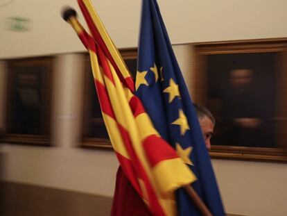 Un trabajador de la sede de la patronal catalana Fomento del Trabajo en Barcelona, coloca unas banderas de Catalu&ntilde;a, Espa&ntilde;a y Europa.
