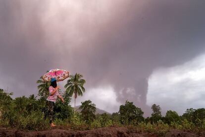 Una mujer observa el volcán Sotupan en erupción en Minahasa, al norte de la isla de Célebes en Indonesia, el 3 de octubre de 2018.  