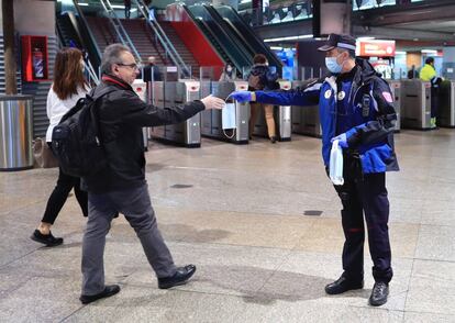 Agentes de policía distribuyen mascarillas de protección entre los usuarios del transporte público, en la estación de Atocha de Madrid.