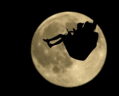 Silhueta de uma menina fotografada em um parque de diversões do Kansas (Estados Unidos) em frente à lua cheia.