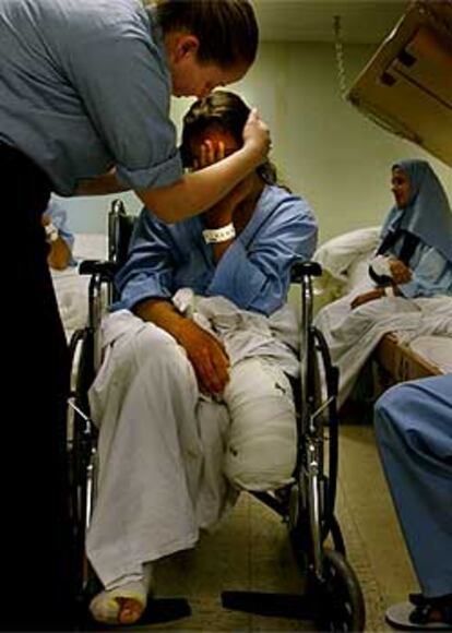 Una mujer a quien le han amputado una pierna es consolada en un hospital.