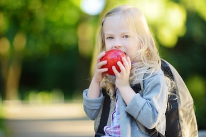 Al cole con el libro y una manzana.