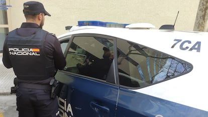 Un agente de la Policía Nacional, junto a un coche patrulla en agosto de 2023.