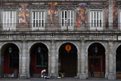 Personas sin hogar se refugian en los arcos de la plaza Mayor de Madrid.