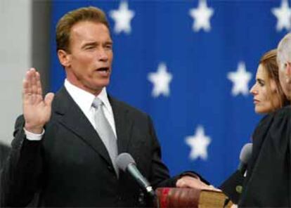 Arnold Schwarzenegger jura su cargo sobre la Biblia, que sostiene su esposa.