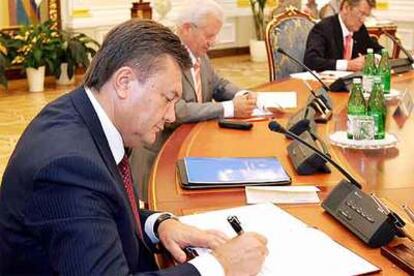 Yanukóvich (izquierda) y Yúshenko (derecha) firman el acuerdo en Kiev.