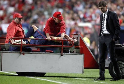 Suffering from a dislocated elbow, Carles Puyol is stretchered past Barça coach Tito Vilanova in Tuesday’s game.