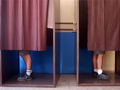 Dos montañeros preparan sus papeletas dentro de la cabina en un colegio electoral de Valencia.