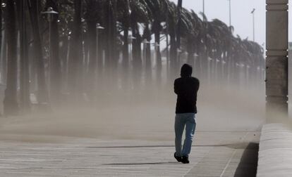 Un hombre camina entre la ventisca de arena por el paseo marítimo de Almería.