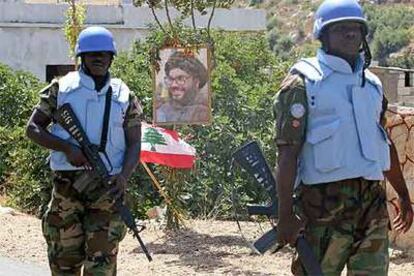 Dos <i>cascos azules</i> pasan ante un cartel con el líder de Hezbolá, Hasan Nasralá, en un puesto de control en Yater, en el sur de Líbano.