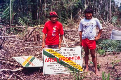 Homens da tribo Araweté junto à placa de demarcação da Terra Indígena Araweté, no Pará