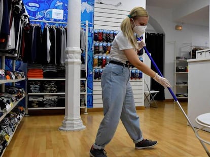 La dueña de una tienda de camisetas en Almería hace una limpieza en uno de los comercios de menos de 400 metros que han retomado su actividad con limitaciones de aforo y la puesta en marcha de medidas de higiene en la fase 1 de la desescalad.