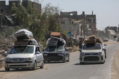 Varios palestinos trasladan sus pertenencias en coches entre edificios en ruinas siguiendo la orden de evacuación dictada por Israel, el pasado lunes en Rafah.