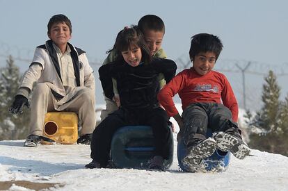 Niños afganos utilizan contenedores de agua como trineos para deslizarse por una colina cubierta de nieve con vistas a Kabul.