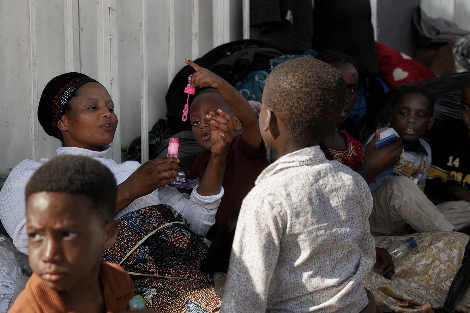 Un grupo de niños y una mujer juegan para matar el tiempo en la acera de Che Guevara Road en la que viven desde que fueron expulsados de su hogar en un ataque xenófobo en Durban (Sudáfrica) el 5 de julio de 2026.