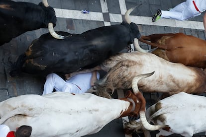 Un mozo es arrollado por los toros de la ganadería Victoriano del Río Cortés durante el cuarto encierro de San Fermín, este jueves.