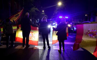 Cinco manifestantes ondean banderas de España en el paso de cebra en calle de Ferraz, mientras el semáforo peatonal está en verde. Jaime Villanueva/El País