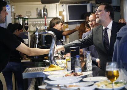 El presidente del Gobierno en funciones, Mariano Rajoy (d), saluda a una persona en un bar, durante un paseo por las calles de San Sebastián.