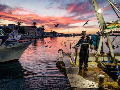Un pescador limpia su barco en el puerto de Molfetta, al sur de Italia.
