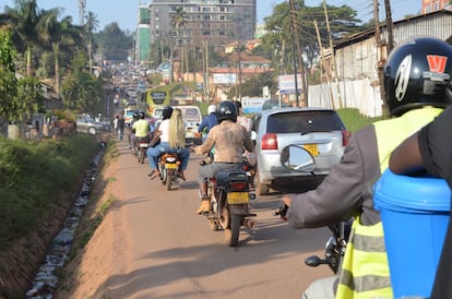 Mototaxis, conocidos localmente como 'boda-boda', pasan junto a vehículos Kampala (Uganda)
