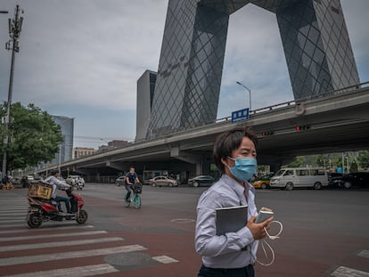 Uma mulher com máscara passa em frente à sede CCTV, a televisão estatal chinesa, um dos edifícios mais emblemáticos de Pequim.