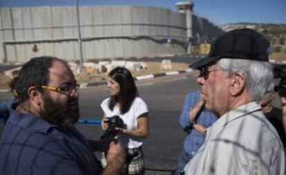 Vargas Llosa (d), junto a Yehuda Shaul ( Breaking the Silence), a la salida de Jerusalén, con el muro divisorio de fondo.