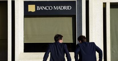 Dos hombres apoyados frente a la sede de Banco Madrid.