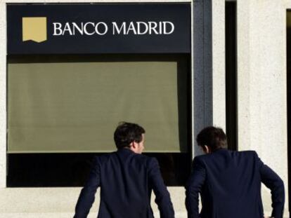 Dos hombres apoyados frente a la sede de Banco Madrid.