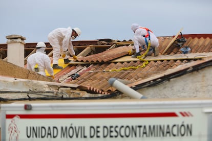 Operarios especializados en la retirada de los tejados de amianto de las tres casas, que se van a derribar en la playa de la babilonia en Guardamar del Segura.