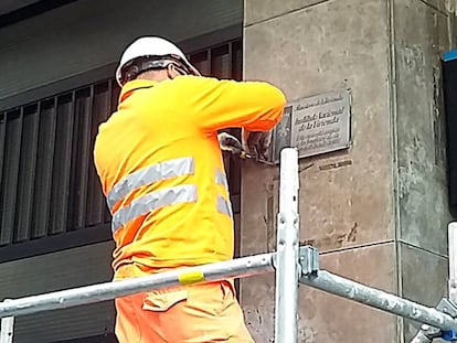 Un operario retira una placa franquista de un edificio de la calle Còrsega de Barcelona.