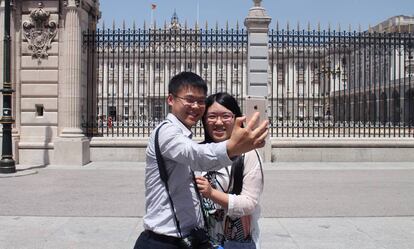 Dos turistas chinos se toman una foto frente al Palacio Real en Madrid.