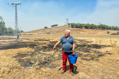 El ganadero José Luis Esteban tras vaciar un balde de agua en parte de un terreno de su propiedad dañado por las llamas.