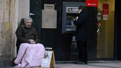 Un mendigo sentado al lado de un cajero, en Madrid. 