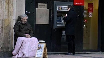 Un mendigo sentado al lado de un cajero, en Madrid. 