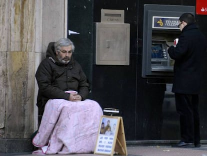 Un mendigo sentado al lado de un cajero, en Madrid.