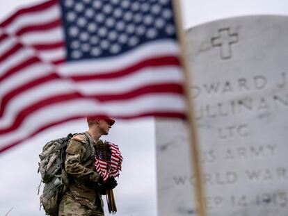 A member of the 3rd U.S. Infantry Regiment places flags in front of each headstone at Arlington National Cemetery in Arlington, on May 25, 2023,  ahead of Memorial Day.