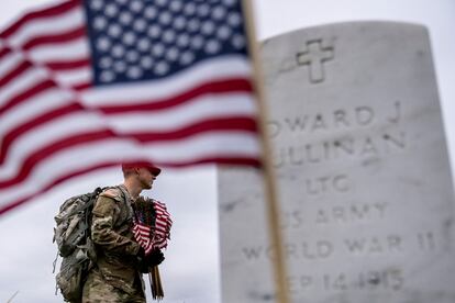 A member of the 3rd U.S. Infantry Regiment places flags in front of each headstone at Arlington National Cemetery in Arlington, on May 25, 2023,  ahead of Memorial Day.